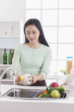 Genç Asyalı kadın mutfakta bulaşık gülümseyen ayakta