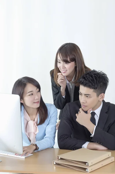 スーツを着た若いアジアの男性と女性が笑顔でコンピュータを見て ストックフォト