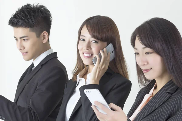 Молодые Азиаты Костюмах Смотрят Мобильный Телефон Одна Улыбается Разговаривая Телефону Лицензионные Стоковые Изображения