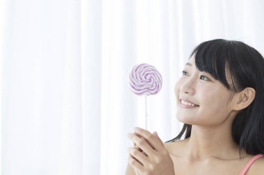 Bir lolipop tutan ve uzağa arıyorsunuz gülümseyen genç kız