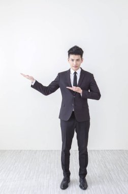 Genç Asyalı adam bir takım elbise eller yukarı giyen ve kameraya gülümseyen