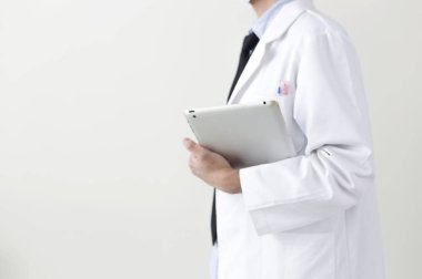 Genç doktor dizüstü bilgisayar tutuyor ve başka yere bakıyor.,