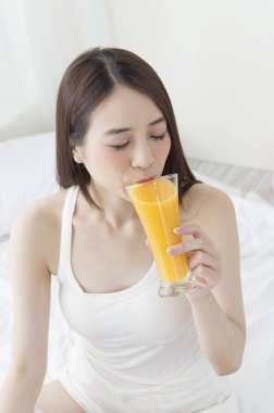 Bir bardak portakal suyu içme gülümseyen Genç Asyalı kadın
