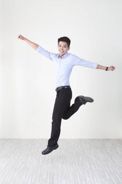 Genç adam bir takım elbise atlama yüksek ve kameraya gülümseyen