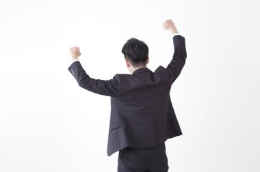 Genç Asyalı adam bir takım elbise eller yukarı giyen ve sırtı kameraya gösteren