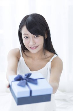 Bir hediye kameraya gösteren gülümseyen genç kız