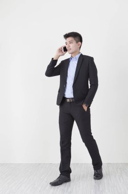 Elbiseli duvara ayakta ve telefonda konuşurken gülümseyen genç adam