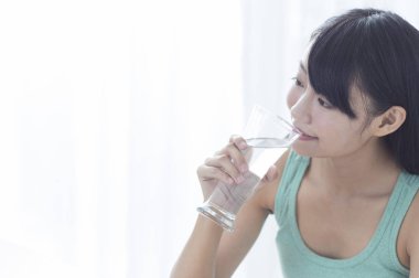 Bir bardak su tutarak ve uzağa arıyorsunuz gülümseyen genç kız