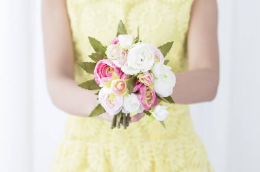 Bir çiçek tutan gülümseyen genç kız