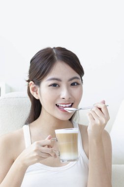 Kahve içme ve kameraya gülümseyen Genç Asyalı kadın