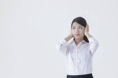 Kulaklarını kapsayan ve uzağa bakarak bir takım elbise giymiş genç Asyalı kadın