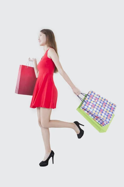 Mujer Joven Con Vestido Rojo Sosteniendo Algunas Bolsas Sonriendo Mirando — Foto de Stock