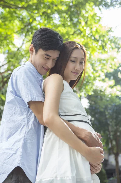 若い父親と妊娠中の母親を抱いて — ストック写真