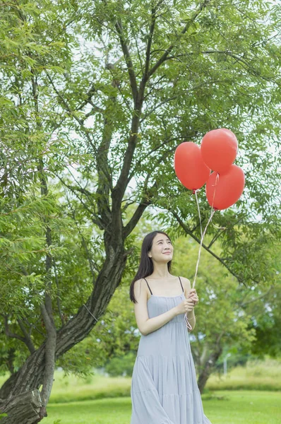 若いアジア女性 風船を押しながらそれを見て笑みを浮かべて — ストック写真