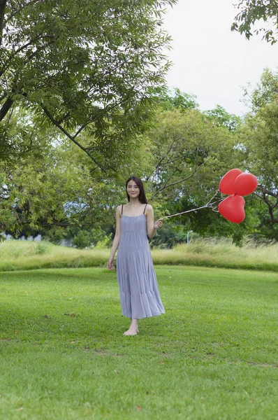 若いアジア女性 風船を押しながらカメラに向かって笑みを浮かべて — ストック写真