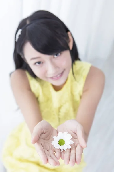 Young girl holding up a flower and smiling showing to the camera