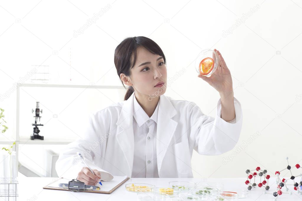 Young female doctor looking at a test tube and writing her note