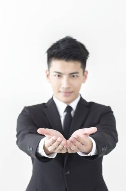 Dayanabiliyor ve kameraya bakarak Genç Asyalı adam bir takım elbise eller