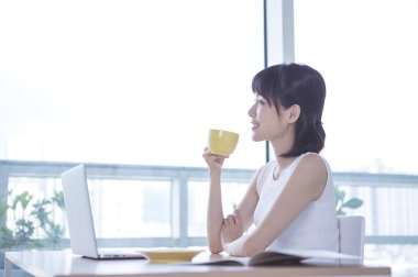 Masada oturan ve içme kahve gülümseyen beyaz elbiseli Genç kadın