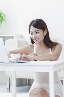 Bir dizüstü bilgisayar kullanarak gülümseyen Genç Asyalı kadın