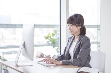 Bilgisayar üzerinde çalışmaya gülümseyen elbiseli Genç kadın