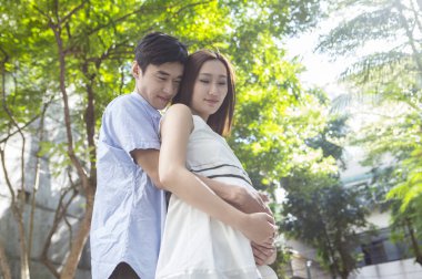 Birlikte sarılma ve gülümseyen hamile anne ve Genç Baba