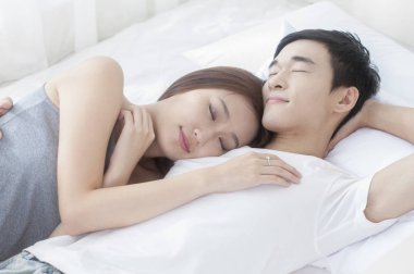 Genç çiftin birbirlerinin sarılma ve gülümseyen yatakta yatıyordu