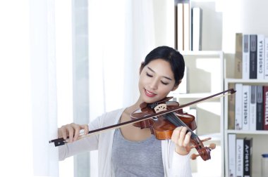 Genç kadın bir Keman çalmaya gülümseyen