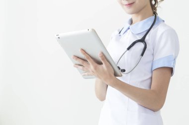 Genç hemşire tableti tutuyor ve gülümsüyor.,