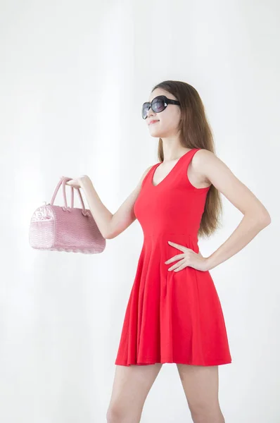 袋を保持している赤いドレスを着た若い女性の手に彼女の腰とよそ見 — ストック写真