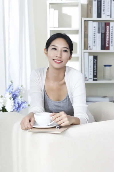 Mujer Joven Sentada Mesa Sosteniendo Una Taza Café Sonriendo Mirando — Foto de Stock