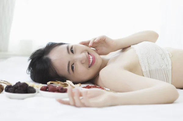 年轻的亚洲妇女躺在一些中药旁边 对着镜头微笑 — 图库照片