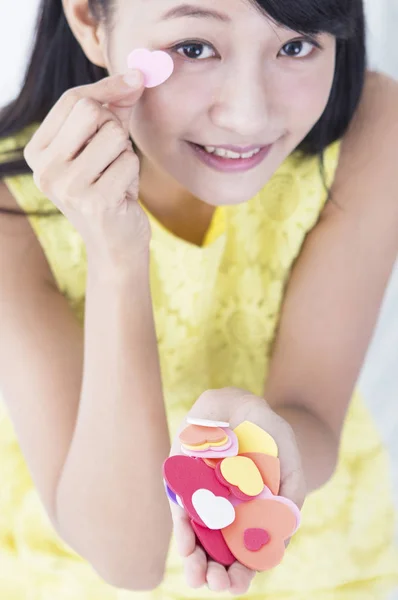 年轻女孩举起一些心形的玩具 对着镜头微笑 — 图库照片