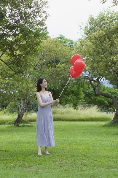 若いアジア女性 風船を押しながらそれを見て笑みを浮かべて — ストック写真