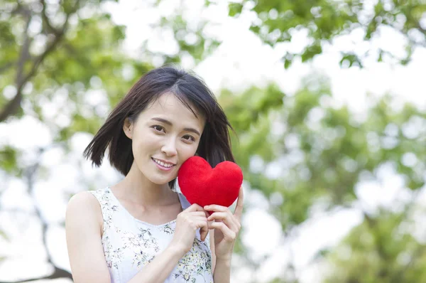年轻的亚洲女子抱着一颗心 对着镜头微笑 — 图库照片