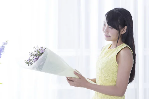 Young girl holding a flower and smiling looking away