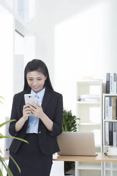 Young woman in a suit smiling using her mobile phone