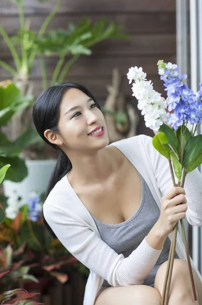 Young woman holding a flower and smiling looking at it