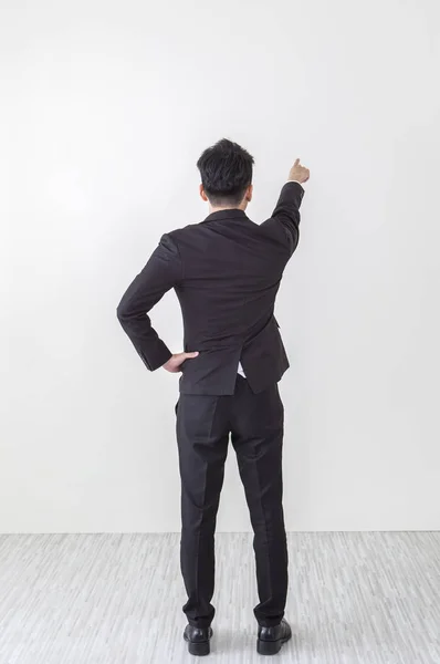 Young Asian man wearing a suit hand up showing his back to the camera