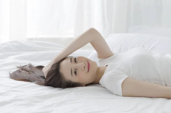 ベッドに横になっていると カメラを見て笑っている若いアジアの女性 — ストック写真