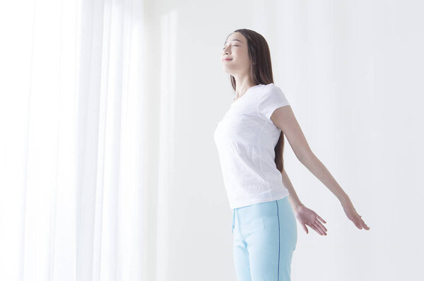 Young Asian woman stretching herself with her eyes closed