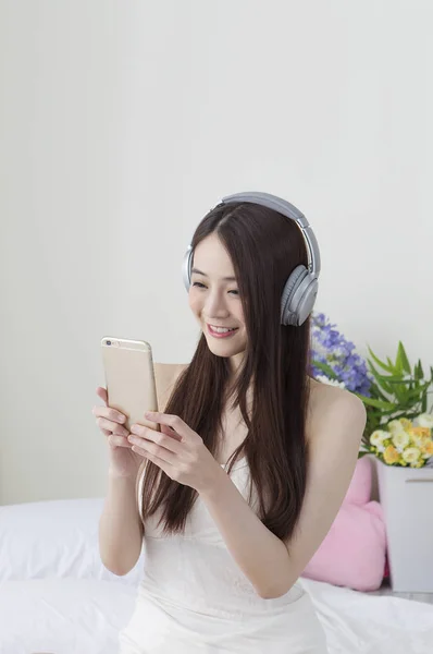 Jovem Mulher Asiática Vestindo Fone Ouvido Sorrindo Usando Seu Telefone — Fotografia de Stock