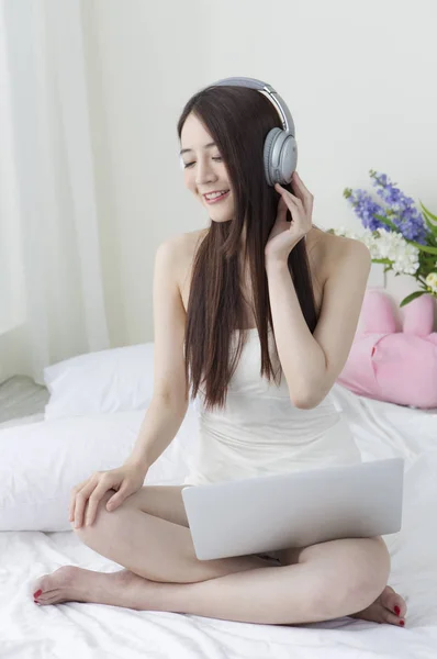 Mladá Asijská Žena Sedící Posteli Nošení Sluchátek Usmívá Přenosném Počítači — Stock fotografie