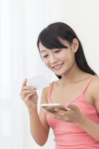 Menina Sorrindo Segurando Smartphone Olhando Para Seu Cartão — Fotografia de Stock