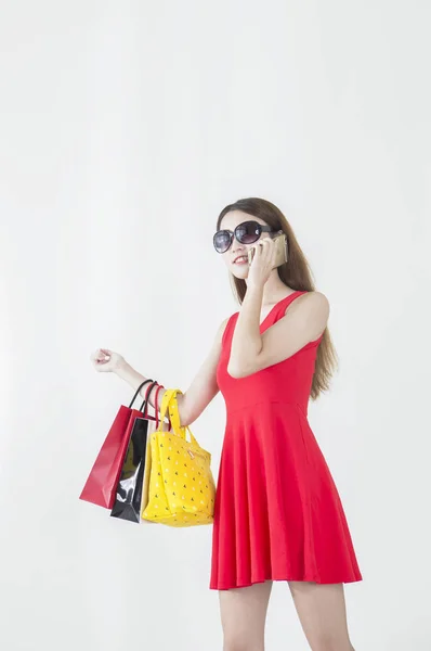 買い物袋を押しながら電話で話して笑っている赤いドレスを着た若い女性 — ストック写真