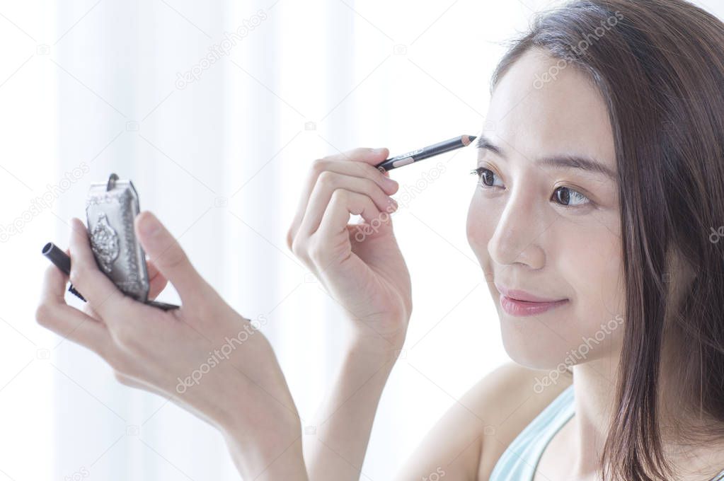 Young Asian woman smiling putting makeups onto her face