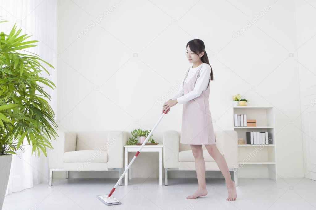 Young Asian woman smiling mopping the floor