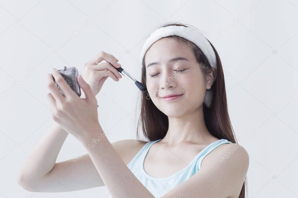 Young Asian woman smiling putting makeups onto her face