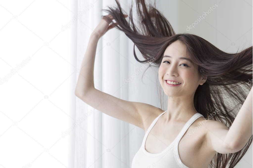 Young Asian woman hands playing with her hair and smiling at the camera