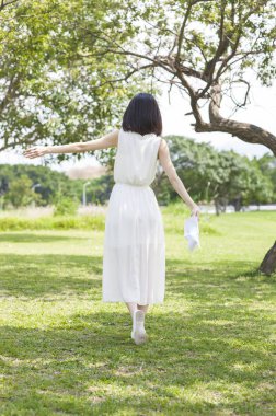 Genç Asyalı kadın el açın ve geri kameraya çimenlerin üzerinde yürüyüş ve ona haddini bildir